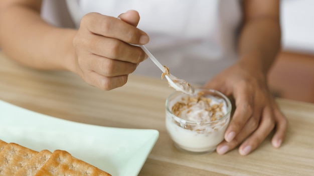 Conceito de estilo de vida em casa Mãos de mulher pegando iogurte e comendo bolachas para lanche em casa