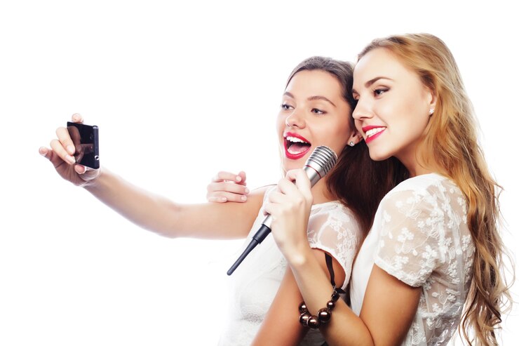 Foto conceito de estilo de vida, felicidade, emoção e pessoas: garotas bonitas com um microfone cantando e fazendo selfie