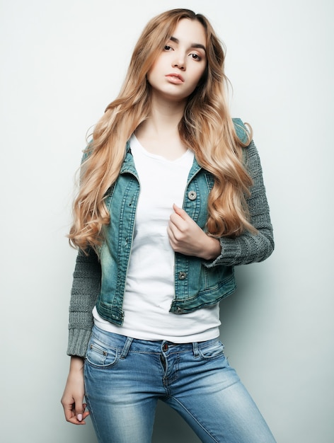 Conceito de estilo de vida, moda e pessoas: linda mulher encaracolada usando roupas casuais, posando em fundo branco