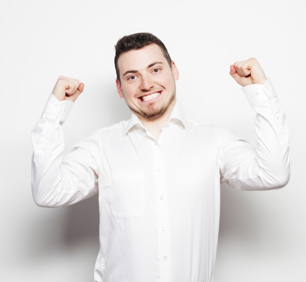 Conceito de estilo de vida, negócios e pessoas: empresário de sucesso. jovem feliz em trajes formais gesticulando e sorrindo em pé contra o espaço em branco