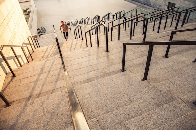 Conceito de estilo de vida saudável de fitness, esporte, exercício e pessoas. Homem correndo lá em cima na cidade.