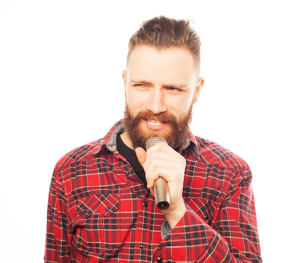 conceito de estilo de vida um jovem com barba vestindo uma camisa branca segurando um microfone e cantando estilo hipster sobre fundo branco