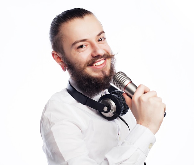 Conceito de estilo de vida um jovem com barba vestindo uma camisa branca segurando um microfone e cantandoIsolado em branco