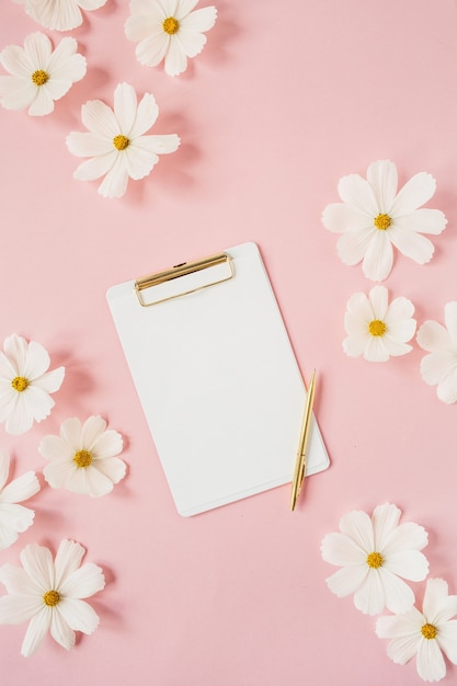 Conceito de estilo mínimo. flores de camomila margarida branca em rosa pálido com pastilhas brancas e caneta dourada. estilo de vida criativo, verão, conceito de primavera