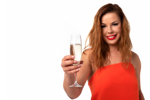 Conceito de evento de celebração mulher jovem e atraente em um vestido laranja com unhas perfeitas segura uma taça de champanhe ou vinho e sorrindo em um espaço de cópia de fundo branco