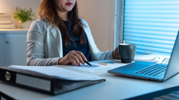 Conceito de excesso de trabalho A mulher de escritório que trabalha em sua mesa apontando sua caneta no papel