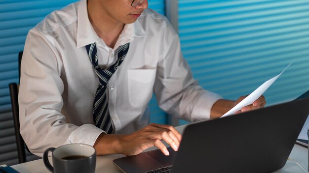 Conceito de excesso de trabalho o pessoal do escritório na gravata solta sentado em sua mesa lendo uma papelada