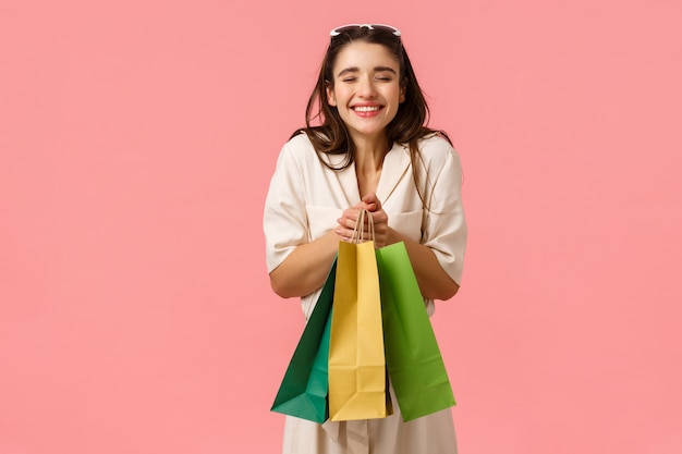 Conceito de excitação, consumo e lojas. Noiva alegre e divertida, compras para o futuro casamento, gritando em êxtase, sorrindo alegremente segurando sacos desfrutando de comprar coisas, de pé rosa