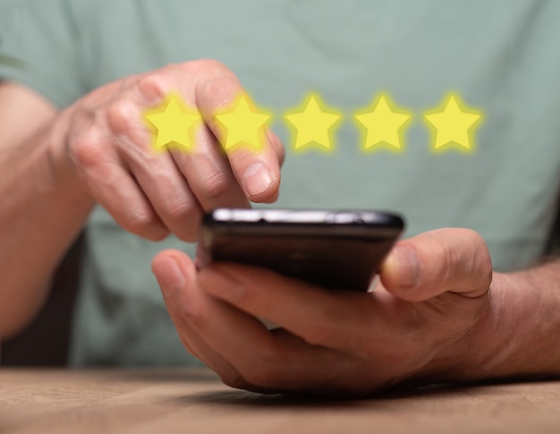 Conceito de experiência positiva do cliente. Avaliação e avaliação de usuários por telefone no celular. Smartphone em mãos masculinas e feedback 5 estrelas.