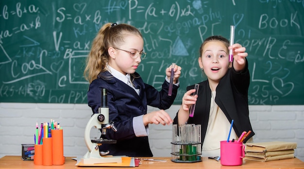 Conceito de experimento químico Medidas de segurança para fornecer reação química segura Crianças geniais trabalham em sua própria teoria química Conhecimento básico de química Alunos garotas bonitas usam tubos de ensaio com líquidos