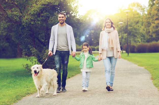 conceito de família, animal de estimação, animal doméstico e pessoas - família feliz com cachorro labrador retriever andando no parque de verão