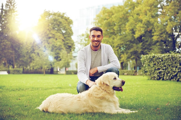 conceito de família, animal de estimação, animal e pessoas - homem feliz com cachorro labrador retriever andando no parque da cidade