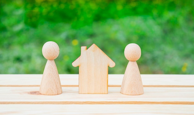 Conceito de família Casa de madeira e pessoas pequenas em uma mesa de madeira com fundo verde