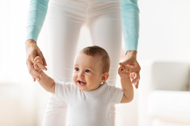 conceito de família, criança, infância e paternidade - bebezinho feliz aprendendo a andar com a ajuda da mãe em casa