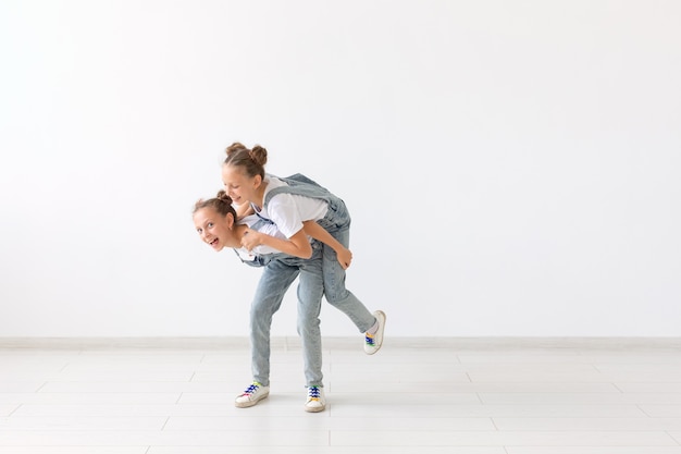 Conceito de família e amor - gêmea feliz dando carona para sua irmã rindo.