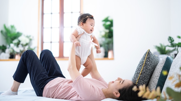 Conceito de família e maternidade jovem feliz mãe asiática com filho pequeno em casa