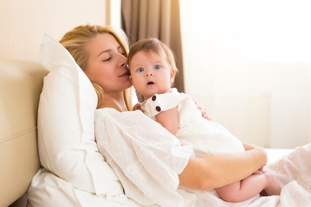 Conceito de família feliz e alegre. Mãe e bebê de três meses se beijando, rindo e se abraçando, close-up retrato