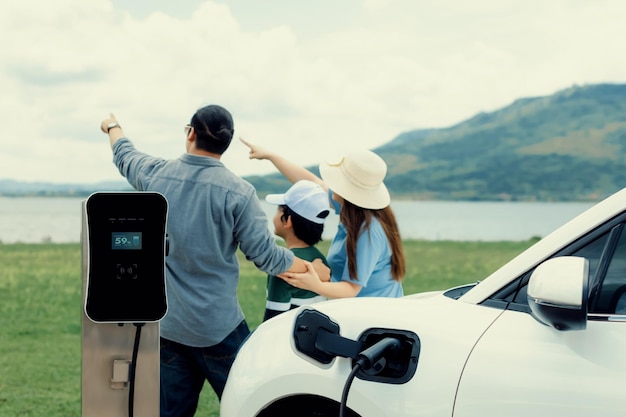 Conceito de família feliz progressiva no lago de campo verde com veículo elétrico