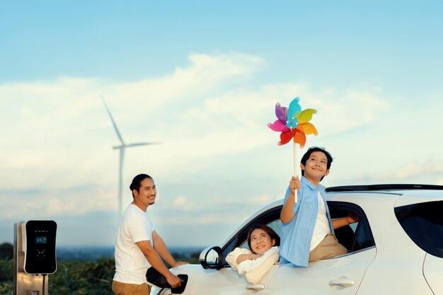 Conceito de família feliz progressiva no parque eólico com veículo elétrico