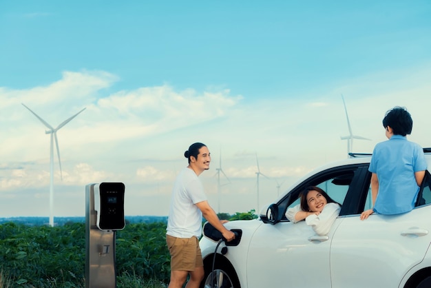 Conceito de família feliz progressiva no parque eólico com veículo elétrico