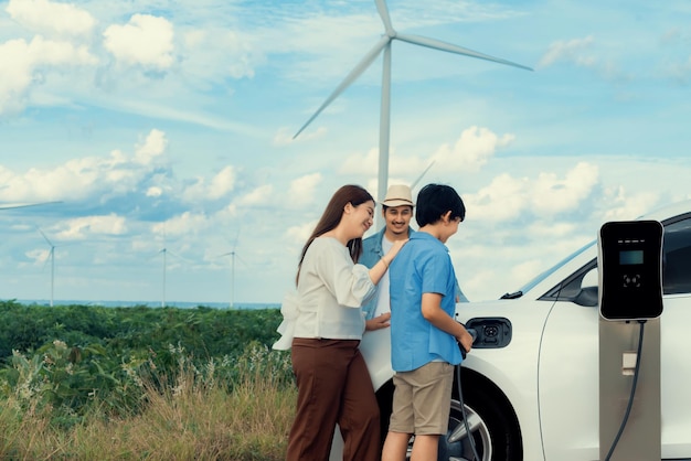 Conceito de família feliz progressiva no parque eólico com veículo elétrico