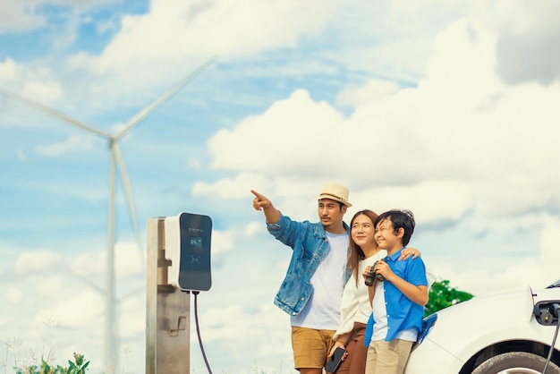 Conceito de família feliz progressiva no parque eólico com veículo elétrico