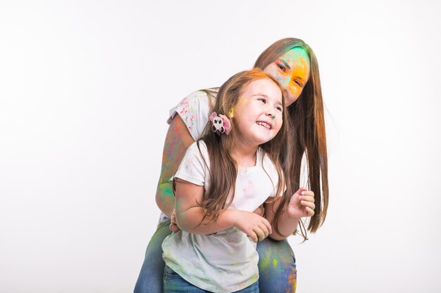 Conceito de família, festival de holi e feriados - mulher e menina sorridente coberta de colorido