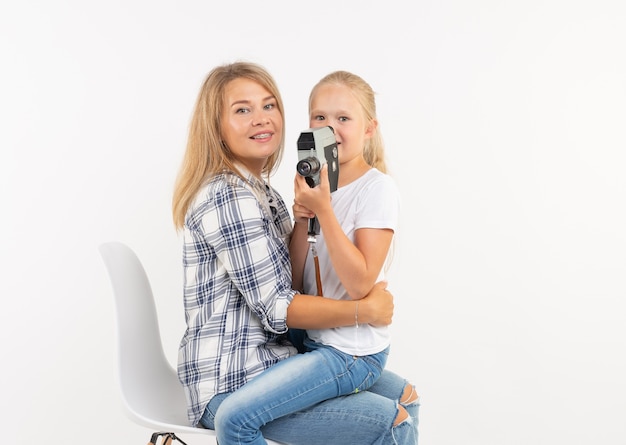 Conceito de família, fotografia e passatempo - mulher e seu filho usando uma câmera antiquada em fundo branco.