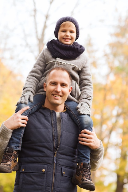 conceito de família, infância, temporada e pessoas - feliz pai e filho se divertindo no parque outono