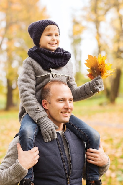 conceito de família, infância, temporada e pessoas - feliz pai e filho se divertindo no parque outono