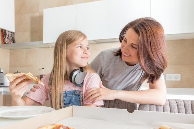 Conceito de família, mãe e filha comendo uma pizza saborosa