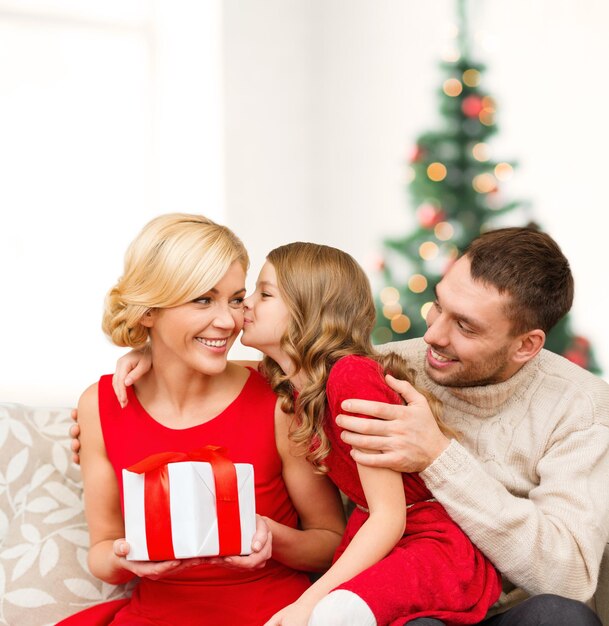 conceito de família, natal, natal, inverno, felicidade e pessoas - adorável criança beija a mãe e dá um presente