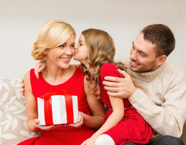 conceito de família, natal, natal, inverno, felicidade e pessoas - adorável criança beija a mãe e dá um presente