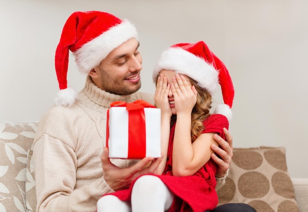 conceito de família, natal, natal, inverno, felicidade e pessoas - filha sorridente com os olhos fechados à espera de um presente da fathe