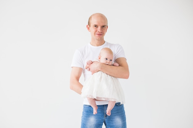 conceito de família, paternidade e filhos - pai careca segurando um lindo recém-nascido na parede branca