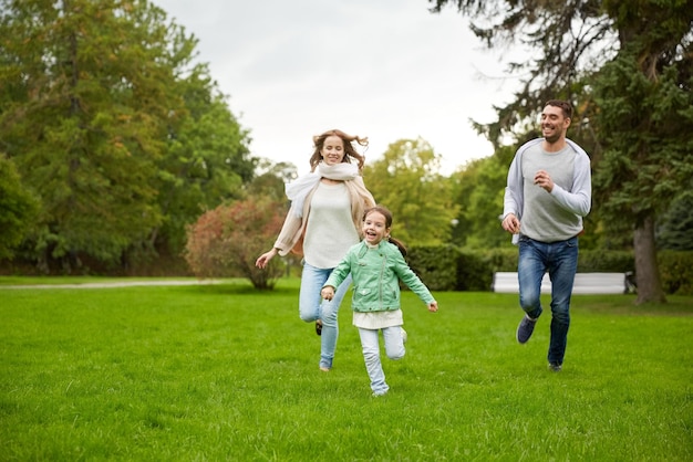 conceito de família, paternidade, lazer e pessoas - feliz mãe, pai e garotinha correndo e jogando jogo de pegar no parque de verão