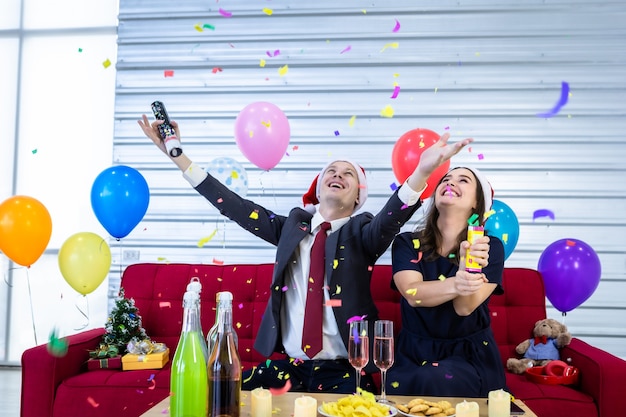 Conceito de feliz ano novo 2021. Casal feliz acendendo fogos de artifício de papel Com champanhe e biscoitos na mesa na festa de Natal e Réveillon