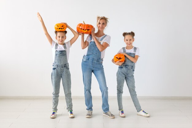 Conceito de feliz dia das bruxas e feriados - uma mãe e suas filhas com abóboras. Família feliz se preparando para o Halloween.