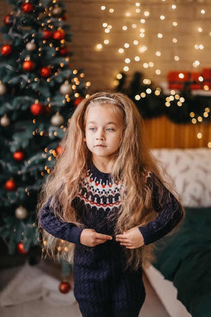 Conceito de feliz natal. a criança está dançando alegremente perto da árvore de natal em casa. celebração de natal feliz em casa.