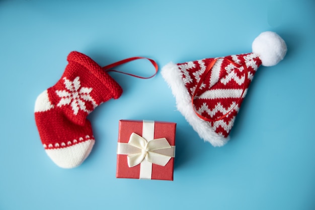 Conceito de feliz natal: caixa vermelha presente e bebê recém-nascido vermelho meia e chapéu em fundo azul