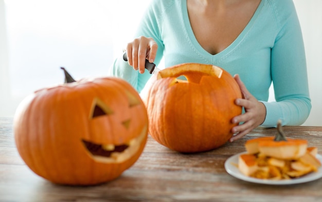 Conceito de feriados, halloween, decoração e pessoas - close-up de mulher com abóboras em casa