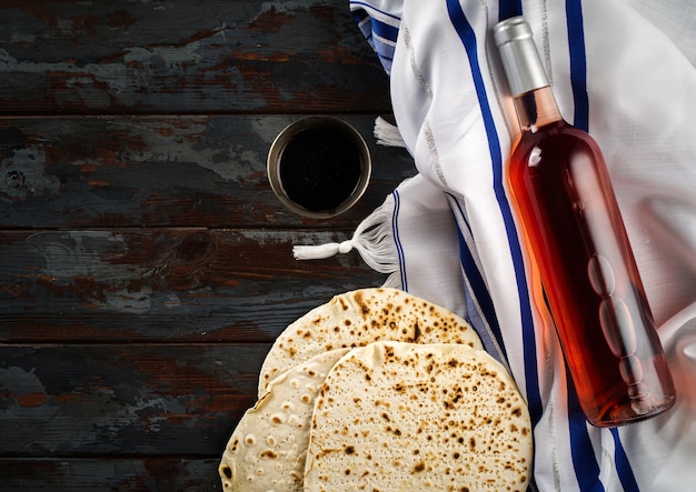 Conceito de férias da Páscoa com vinho e matzoh sobre fundo rústico, plano leigo.