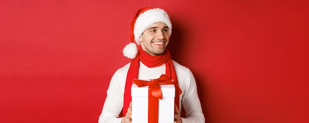 Conceito de férias de inverno natal e estilo de vida fechado de homem atraente com chapéu de papai noel e cachecol