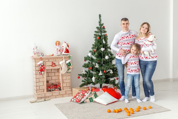 Conceito de férias - feliz família mãe pai e filho na árvore de Natal em casa.