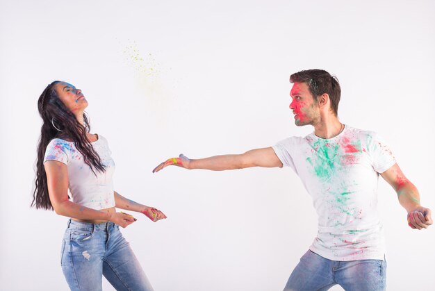 Conceito de férias, feriado e pessoas - casal feliz se divertindo coberto de tinta na superfície branca