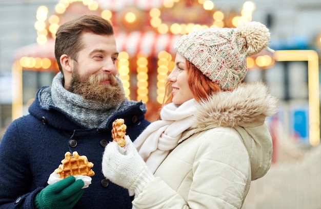 Conceito de férias, inverno, natal e pessoas - casal feliz em roupas quentes caminhando pela cidade velha