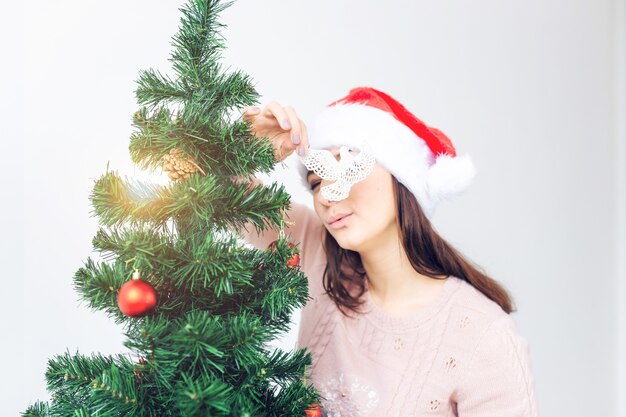 Conceito de férias - menina com chapéu de Papai Noel decorada árvore de Natal. A espera do Natal.