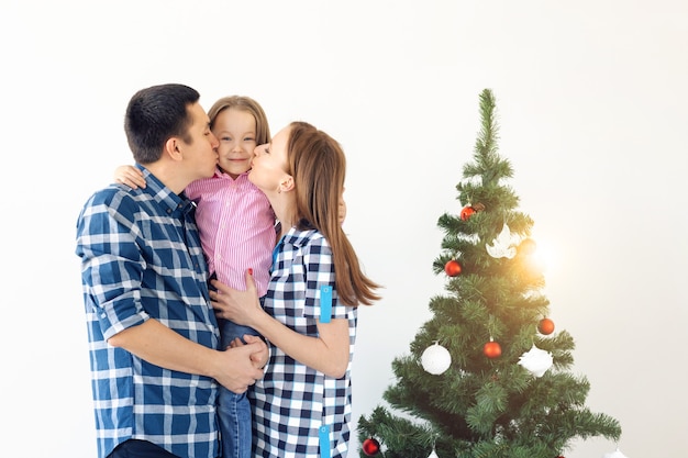 Conceito de férias, presentes e árvore de Natal - família pequena se divertindo juntos no Natal