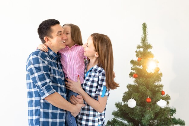 Conceito de férias, presentes e árvore de natal - família pequena se divertindo juntos no natal