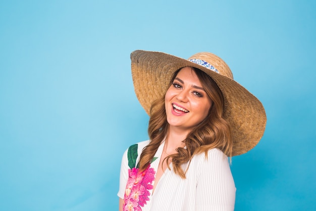 Conceito de férias, verão, moda e pessoas - garota com chapéu de palha de roupas da moda. Retrato de uma mulher encantadora sobre fundo azul com espaço vazio da cópia.